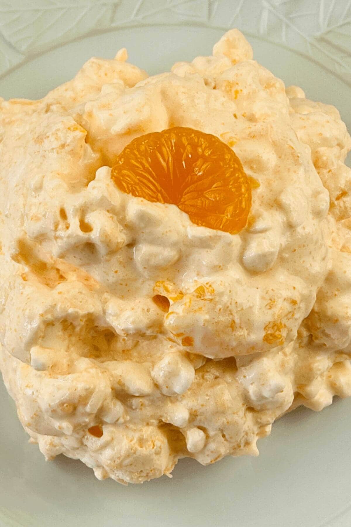 A mandarin orange slice on top of orange fluff.