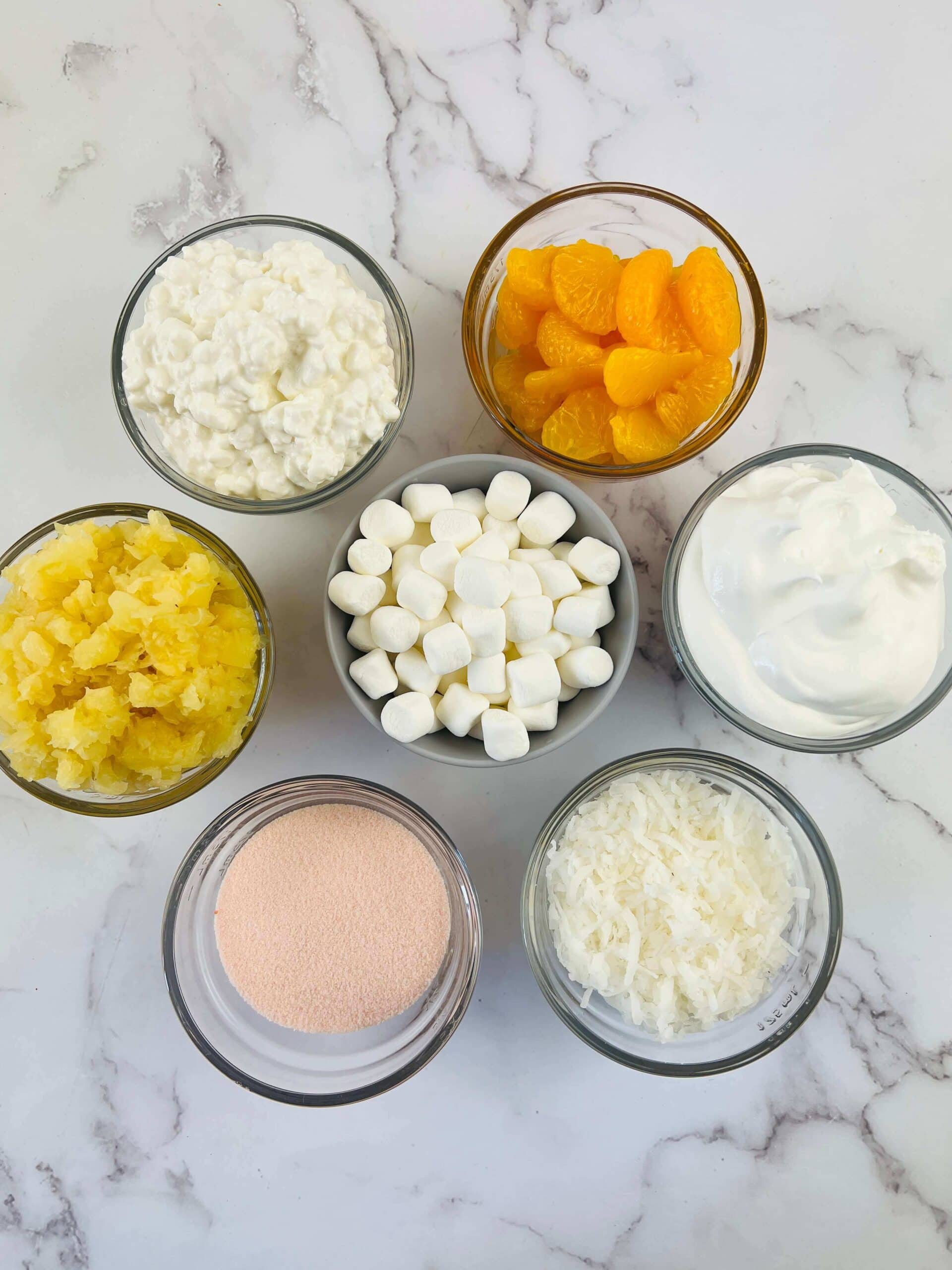 Clear dish full of gelatin, fruit, marshmallows and coconut for the dish.