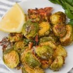 A weadge of lemon next to the parmesan crusted brussels sprouts.