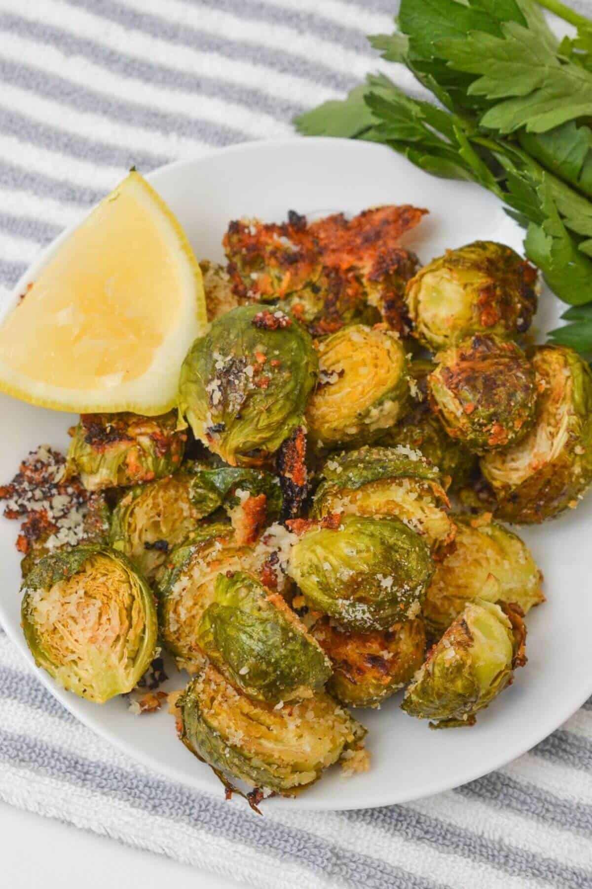 A weadge of lemon next to the parmesan crusted brussels sprouts.