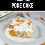 A slice of Pumpkin Poke Cake topped with white frosting and pecans sits on a white plate, while a baking dish of the cake is seen in the background.
