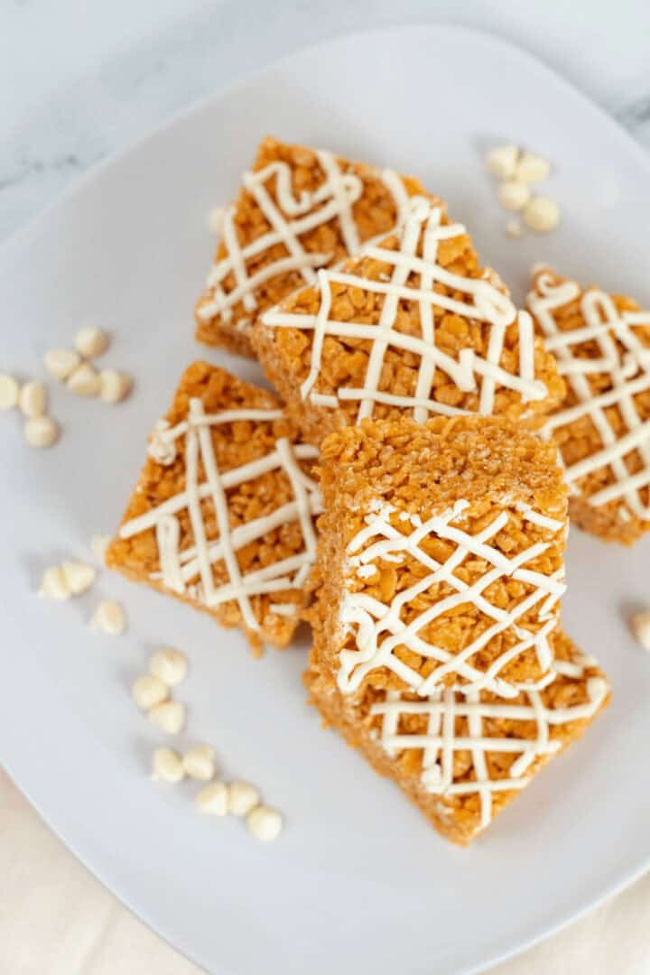 A stack of pumpkin rice krispy treats on a white platter.