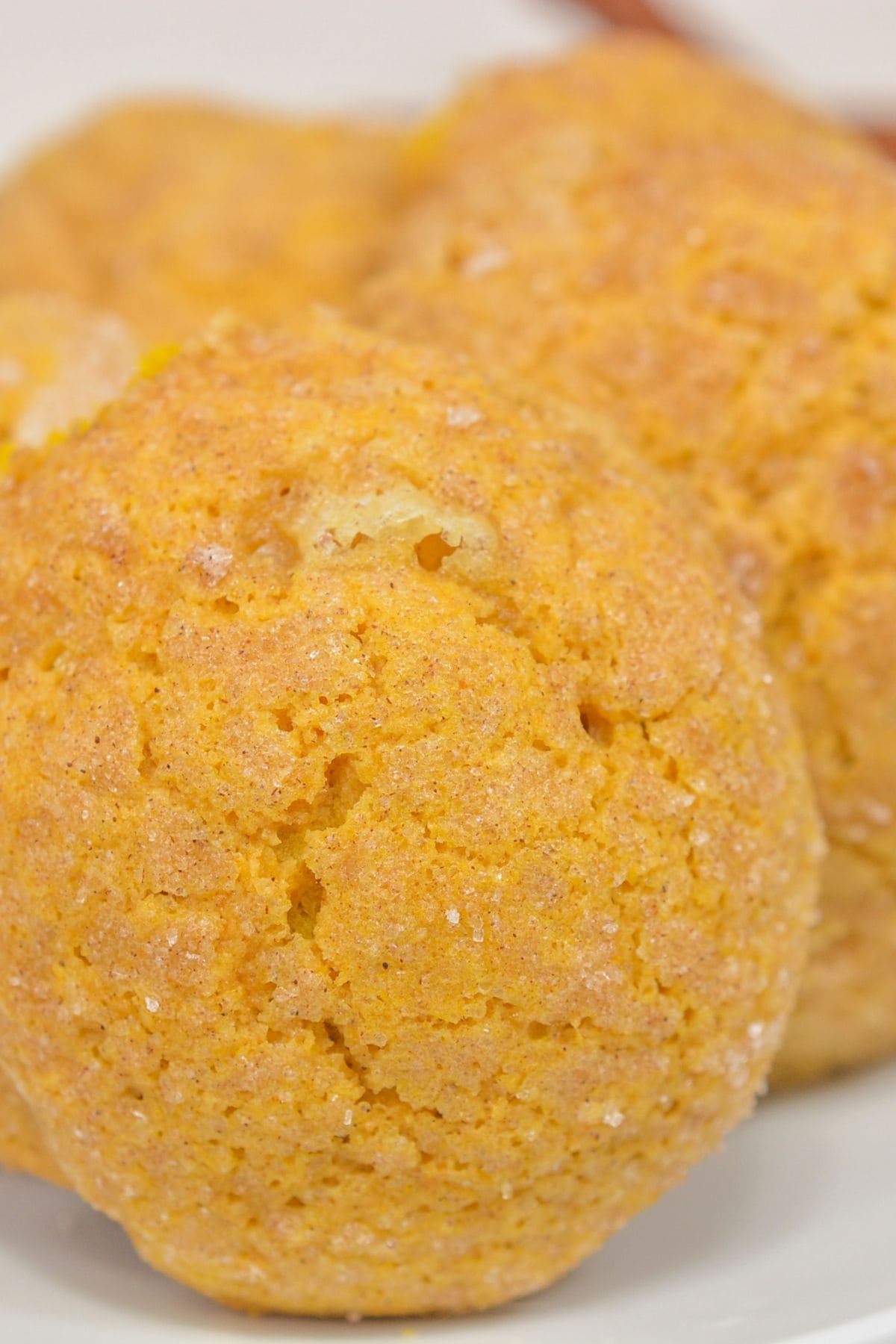 Close-up of a round, golden-brown Pumpkin Snickerdoodle Cookie with a slightly cracked surface and visible sugar crystals.