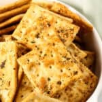A bowl filled with seasoned ranch spicy crackers, featuring a golden-brown color and sprinkled with herbs and spices.