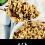 A spoonful of flavorful Rice Dressing with vegetables and herbs held above a bowl of the same dish. Text at the bottom reads "RICE DRESSING.