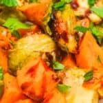 A close-up of roasted Brussels sprouts and sweet potato chunks, garnished with chopped fresh parsley—perfect for anyone who loves roasted vegetables.