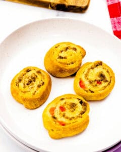 Four sausage crescent rolls on a white plate.