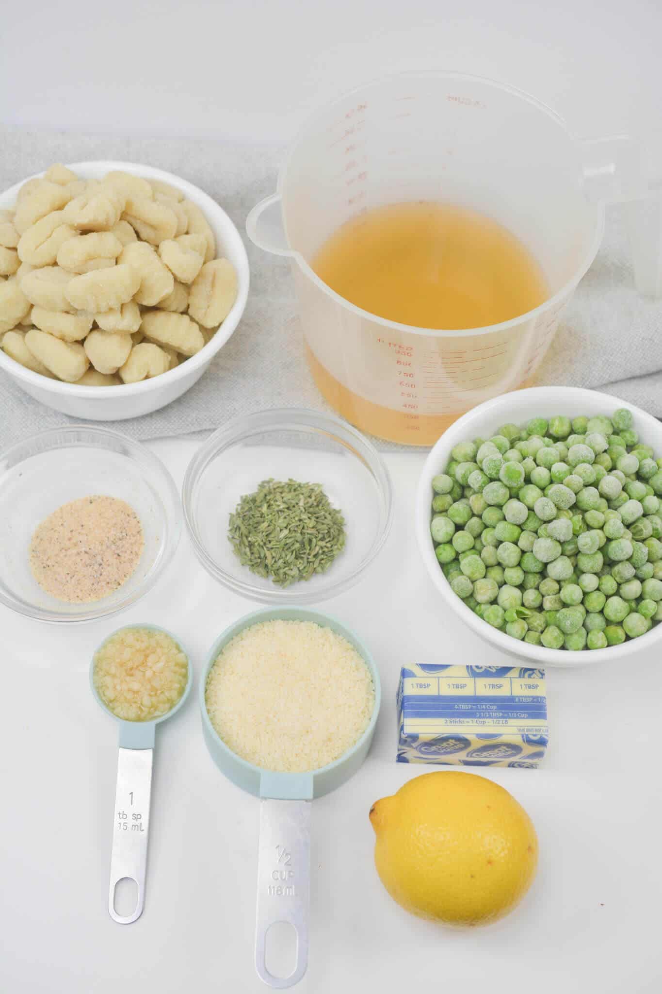 White bowls with the peas, gnocchi and seasonings for the skillet dish.