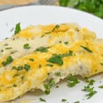 Plate of two tubes topped with melted cheese and garnished with chopped cilantro.