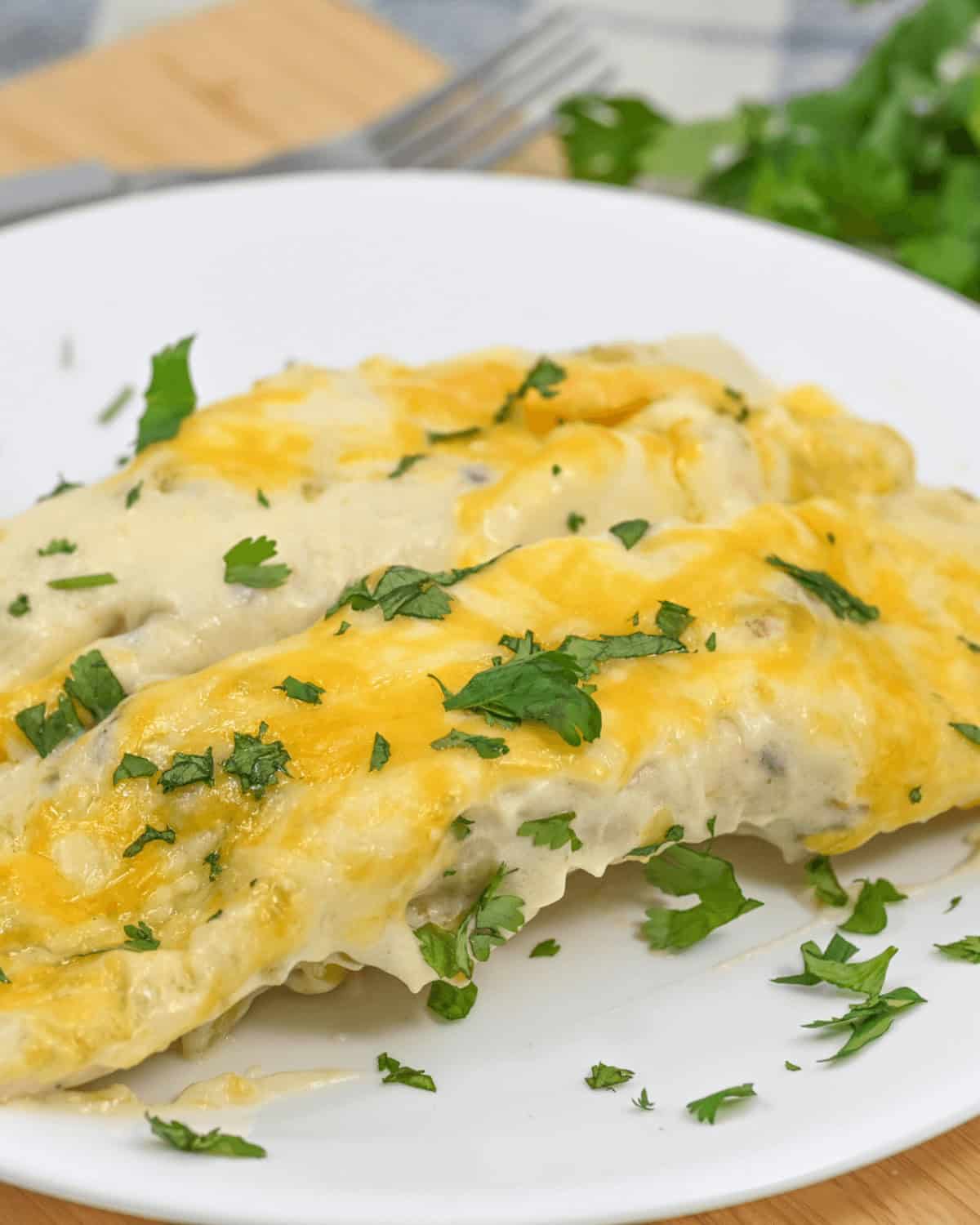 Plate of two tubes topped with melted cheese and garnished with chopped cilantro.