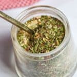 A jar of the spaghetti seasoning blend with a spoon in it.