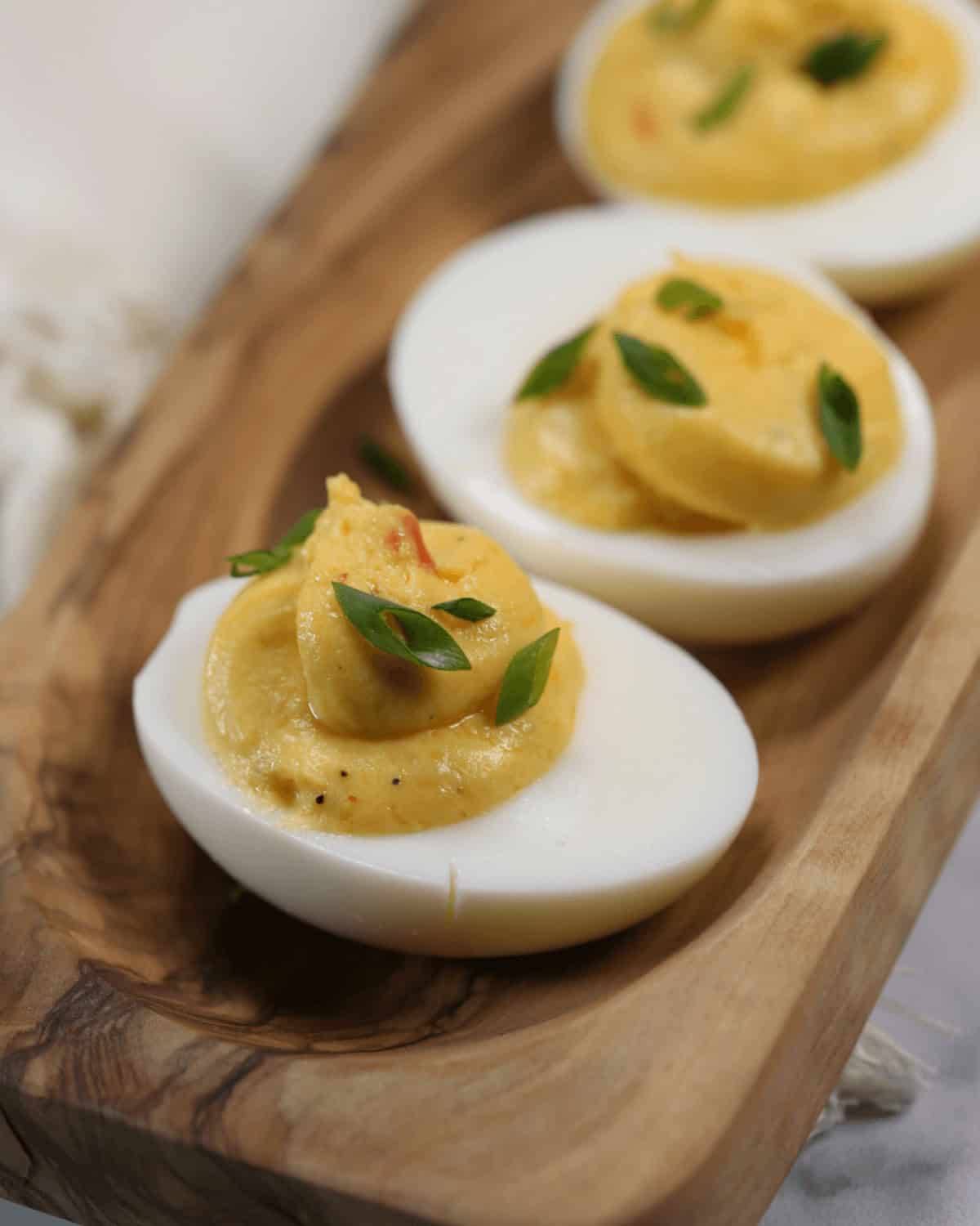 a tray of appetizers with paprika and fresh herbs on a wooden serving platter.