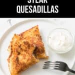 Two savory steak quesadilla wedges on a white plate, served with a side of sour cream and a black fork. Text above reads "Favorite Steak Quesadillas.