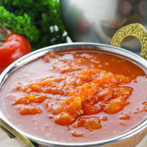 A metal bowl filled with stewed tomatoes.