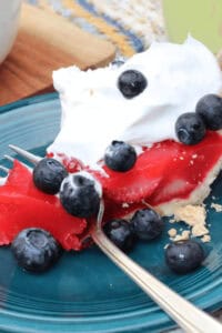 A strawberry Jello pie with whipped cream and blueberries on top.