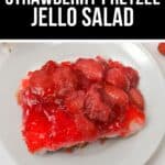 A slice of Pretzel Jello Salad with a red strawberry topping, creamy middle layer, and crunchy pretzel crust sits on a white plate.