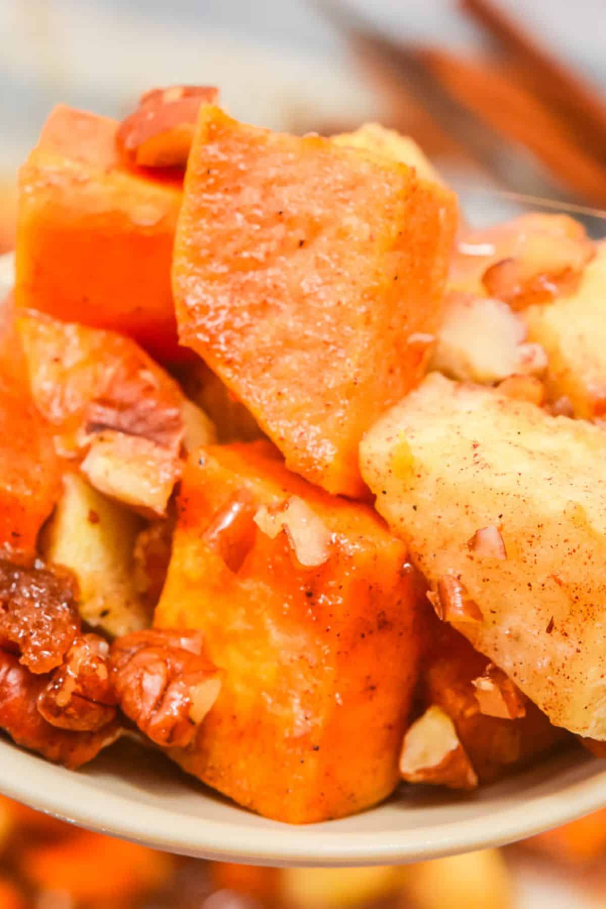 Close-up of a delicious Sweet Potato Apple Casserole, featuring baked sweet potatoes and apples mixed with chopped pecans and cinnamon.