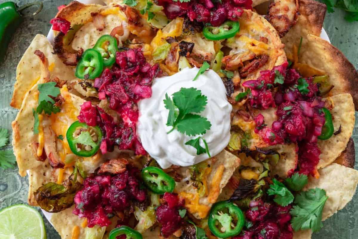 A top view of some Thanksgiving leftovers nachos, with turkey, cranberry sauce, and jalapenos.