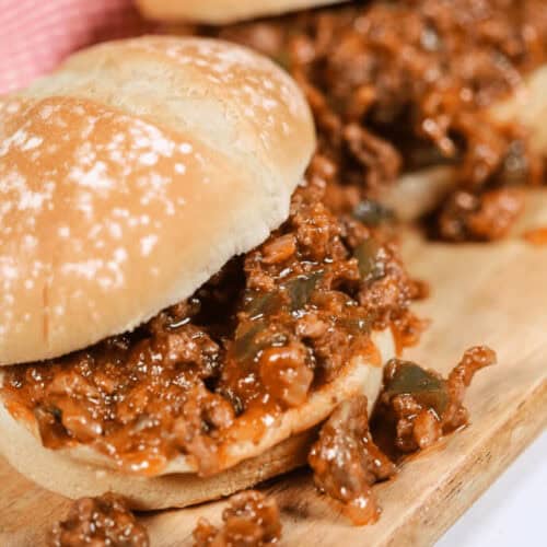 Two delicious Wimpies, also known as Easy Sloppy Joes, filled with a savory mixture of ground meat, onions, and green peppers on a wooden board.