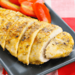 Baked meat served on a black plate with tomatoes.