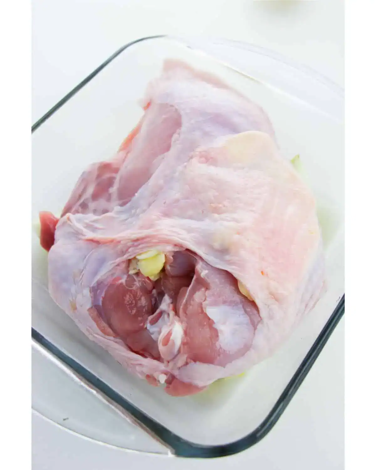 Slow Roasted Turkey Breast with skin, arranged in a clear glass baking dish on a white surface.